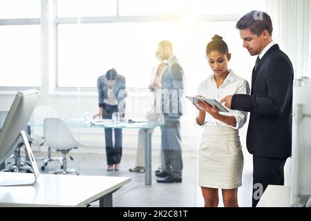 Preparing for their presentation. two businesspeople looking at a digital tablet before a meeting. Stock Photo
