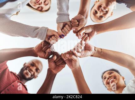 Teamwork, unity and hands or fist for support, trust and community below blue sky. Diversity group men and women friends standing together for Stock Photo