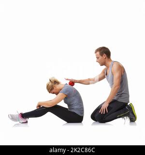Rolling out her muscles. A young man using a massage ball on his female friends back. Stock Photo