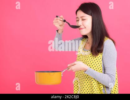 young woman housewife Wearing Kitchen Apron while cooking Stock Photo