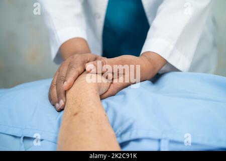 Doctor holding touching hands Asian senior or elderly old lady woman patient with love, care, helping, encourage and empathy at nursing hospital ward, healthy strong medical concept Stock Photo