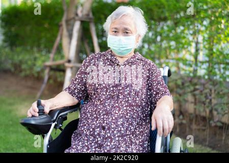 Asian senior or elderly old lady woman patient on electric wheelchair with remote control and wearing a face mask for protect safety infection Covid 19 Coronavirus. Stock Photo
