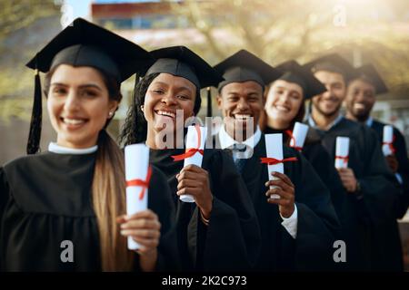 Our future is secure. Portrait of a group of young students holding their diplomas on graduation day. Stock Photo