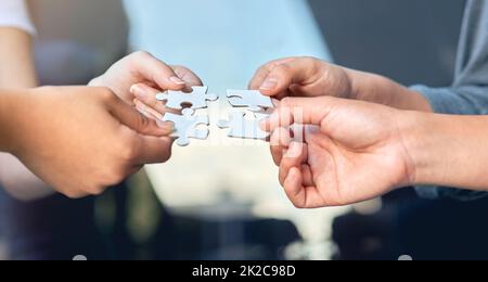 Lets put it all together. Closeup of businesspeople about to put four puzzle pieces together. Stock Photo