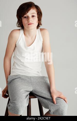 Hes cool and casual. Portrait of a young boy sitting on a stool in the studio. Stock Photo