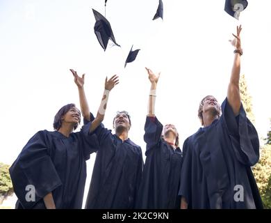 Our hard work has paid off. A group of university graduates throwing their hats in celebration. Stock Photo