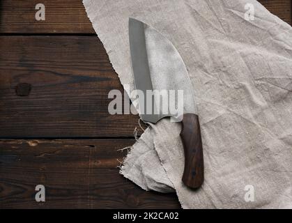metal sharp kitchen knife in a wooden handle on a brown table made of boards Stock Photo