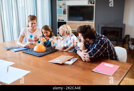 Shes going to take over the world one day. Shot of a beautiful young family working together on a science project at home. Stock Photo