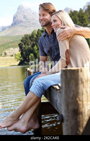 Lakeside loving. Shot of a loving mature couple sitting on a pier out on a lake in the countryside. Stock Photo