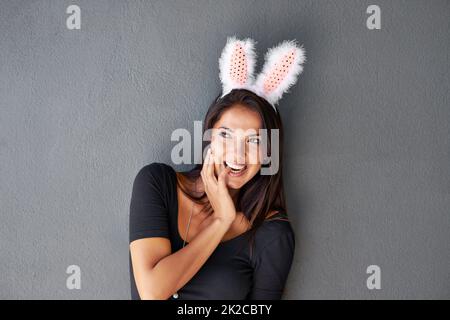 Fluffy seduction in a black dress. a gorgeous brunette wearing bunny ears. Stock Photo