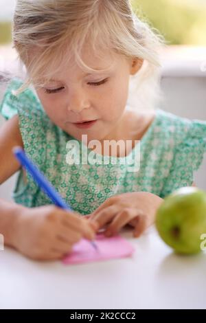 An artist in the making. A cropped shot of a cute little girl drawing on a pink piece of paper. Stock Photo