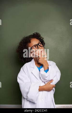 Dreaming of his bright future. An ethnic boy wearing glasses and a lab coat looking contemplative - copyspace. Stock Photo