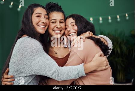 Were like a family of friends. Shot of three happy young sisters embracing at a cafe. Stock Photo