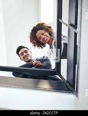 Hi from up here at the top. Low angle portrait of two coworkers leaning on a stairwell bannister. Stock Photo