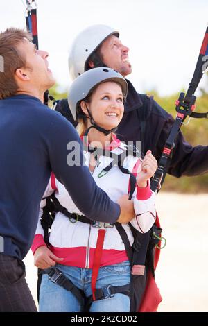 Taking off. Two paragliders ready to do a tandem jump being assisted by an instructor. Stock Photo