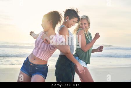 We only have fun on days ending with y. Shot of three friends spending the day at the beach. Stock Photo