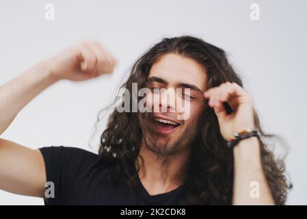 Live your best life. Studio shot of a handsome young man looking cheerful and dancing against a grey background. Stock Photo