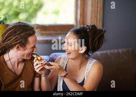 Theres nothing as tasty as pizza. Shot of a Rastafarian couple eating pizza. Stock Photo