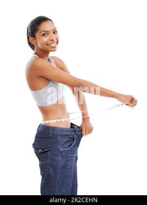 Losing weight every day. A young woman in an oversized pair of pants measuring her waist. Stock Photo