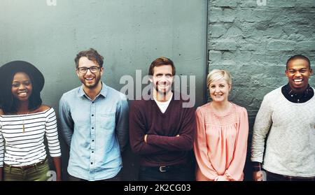 We stand up for diversity. Shot of a diverse group of people standing together against a gray wall. Stock Photo