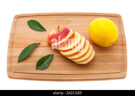 apple tasty, fresh and juicy with green leaves and lemon on a cutting board made of wood. Stock Photo