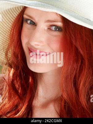 Fiery summer. A young redheade woman wearing a sunhat. Stock Photo