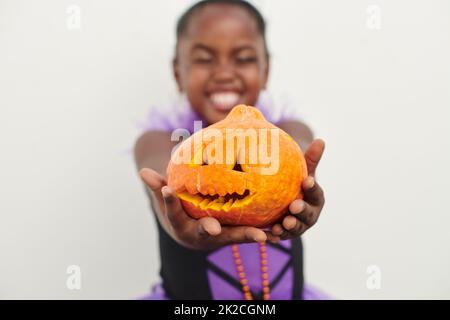 Cutest pumpkin in the patch. Shot of a little girl holding a jack o lantern against a white background. Stock Photo
