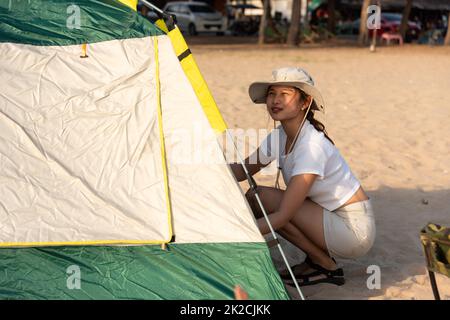 Happy friends pitch tent on sand at beach together to sea in holiday vacation time at sunset Stock Photo