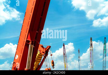 Crawler crane against blue sky and white clouds. Real estate industry. Crawler crane use reel lift up equipment in construction site. Crane for rent. Crane dealership for construction business. Stock Photo