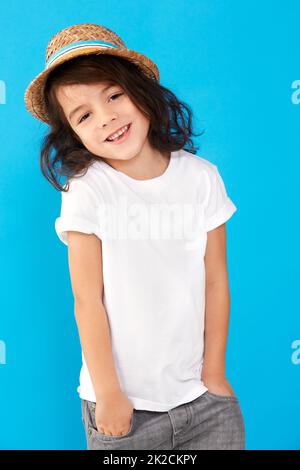 Casual cutie. Portrait of a cute little boy wearing a hat against a blue background. Stock Photo