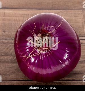Single whole vegetable of red onion on a wooden kitchen board, close up Stock Photo