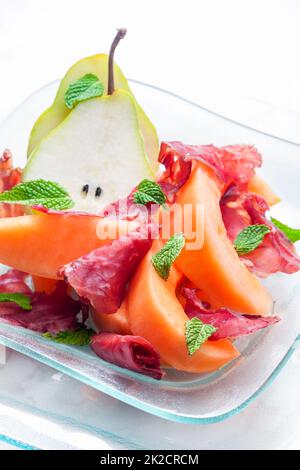 melon cantaloupe and pear with  proscutto and mint leaves Stock Photo