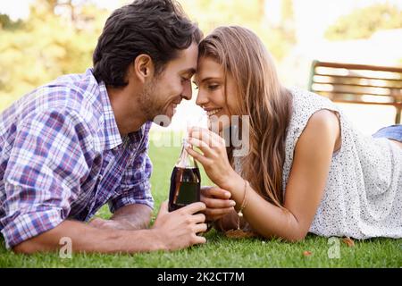 Young love. A happy young couple sipping cola together in the park. Stock Photo