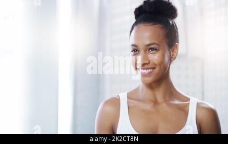 Beauty personified. Shot of an attractive young woman admiring her face in the bathroom at home. Stock Photo