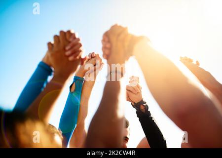 Lets stand together. Shot of a group of unrecognizable people holding hands together in the air. Stock Photo