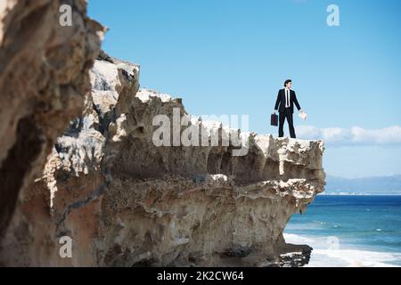 Taking time to put my priorities in perspective. Businessman standing on the edge of a cliff looking out over the ocean while holding a briefcase. Stock Photo