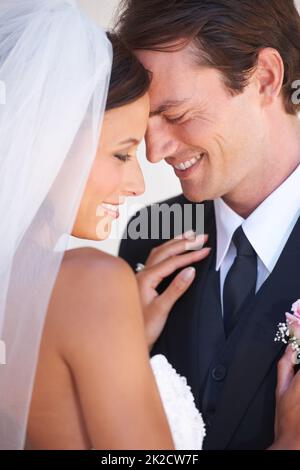 Taking a moment to reflect on their love. A happy newlywed couple sharing a tender moment. Stock Photo