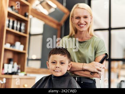 He went for his first official haircut today. Portrait of an adorable little boy getting a haircut at a salon. Stock Photo