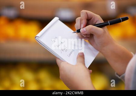 Ticking off her items as she goes along. Closeup shot of a woman checking her shopping list in a grocery store. Stock Photo