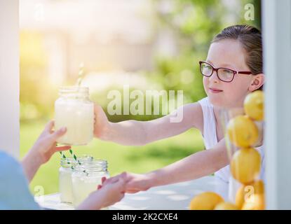 Here you go - enjoy. Cropped shot of a little girl selling lemonade from her stand outside. Stock Photo