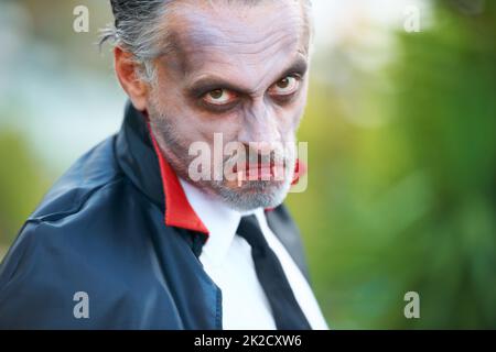 Never too old to join the fun. Mature man dressed up as Dracula for Halloween, scowling at the camera. Stock Photo