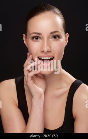 Pleasantly surprised at your brilliant Skin care product prices. Studio shot of an attractive woman isolated on black. Stock Photo