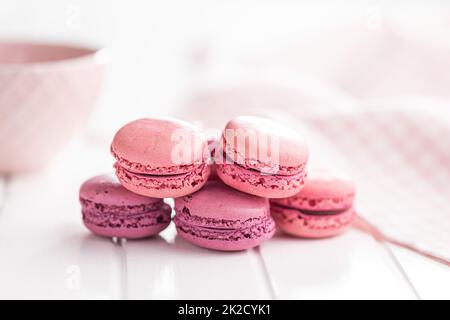 Sweet pink macarons. Traditional french macaroons. Tasty dessert on white table. Stock Photo