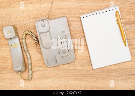 Vintage telephone and blank notebook on wooden background Stock Photo