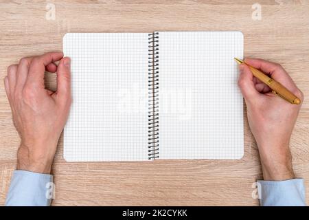Hand writing in squared notebook with pen on wooden background Stock Photo
