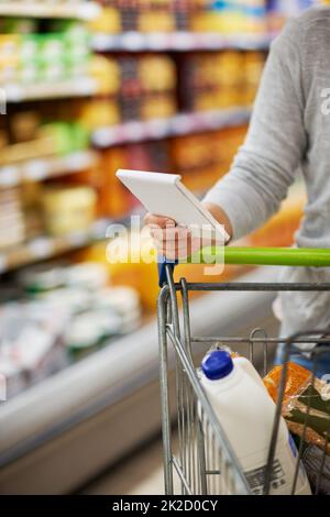 Ensuring she gets everything needed. Closeup shot of a woman checking her shopping list in a grocery store. Stock Photo
