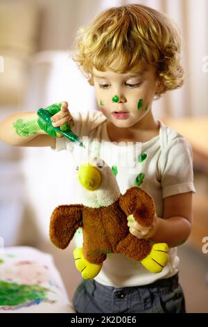 Creativity doesnt play by the rules. Shot of an adorable little boy making a mess while painting. Stock Photo