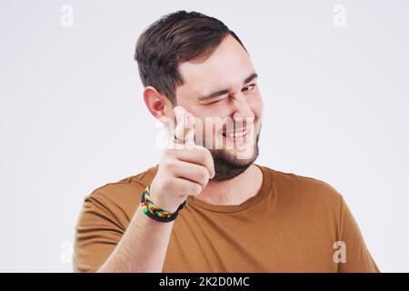 Youre the main man. Portrait of a handsome young man winking and pointing to the camera against a grey background. Stock Photo