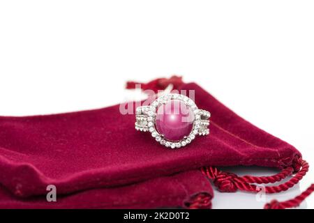 Ruby stone with diamonds ring on red velvet bag. Collection of natural gemstones accessories. Studio shot Stock Photo