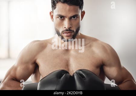 Fighter, sport and boxing gloves on strong man or athlete boxer doing serious training, exercise and muay thai in gym or fitness club. Portrait Stock Photo